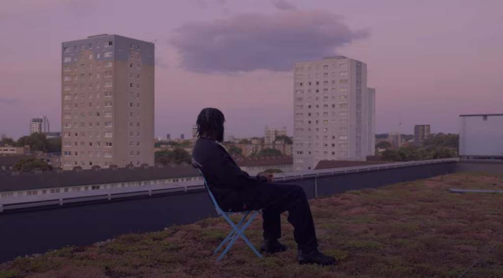 Image of poet Caleb Femi sitting on a rooftop at dusk
