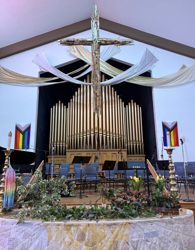 Large cross with white and gold swaggeries and altar covered in greenery
