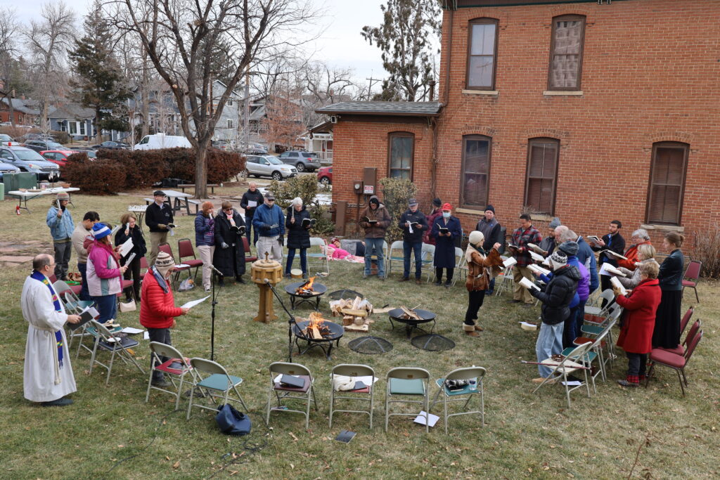 Congregation of First Church gathered around fire pits on the lawn for worship.
