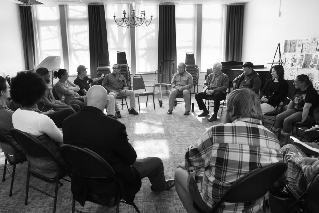 Black and white photo of illuminators hosting a circle discussion in the Parlor