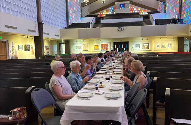 Congregation eating at tables down the center aisle of the sanctuary