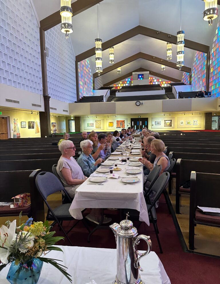 Congregation eating at tables down the center aisle of the sanctuary
