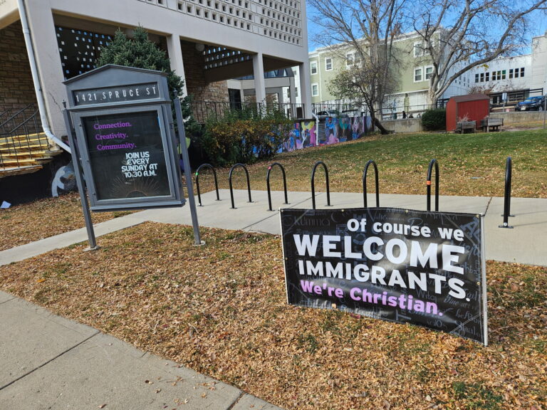 Yard banner in front of First Church reading "Of course we welcome immigrants. We're Christian."