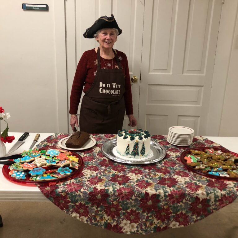 Volunteer behind a table of cookies and cake